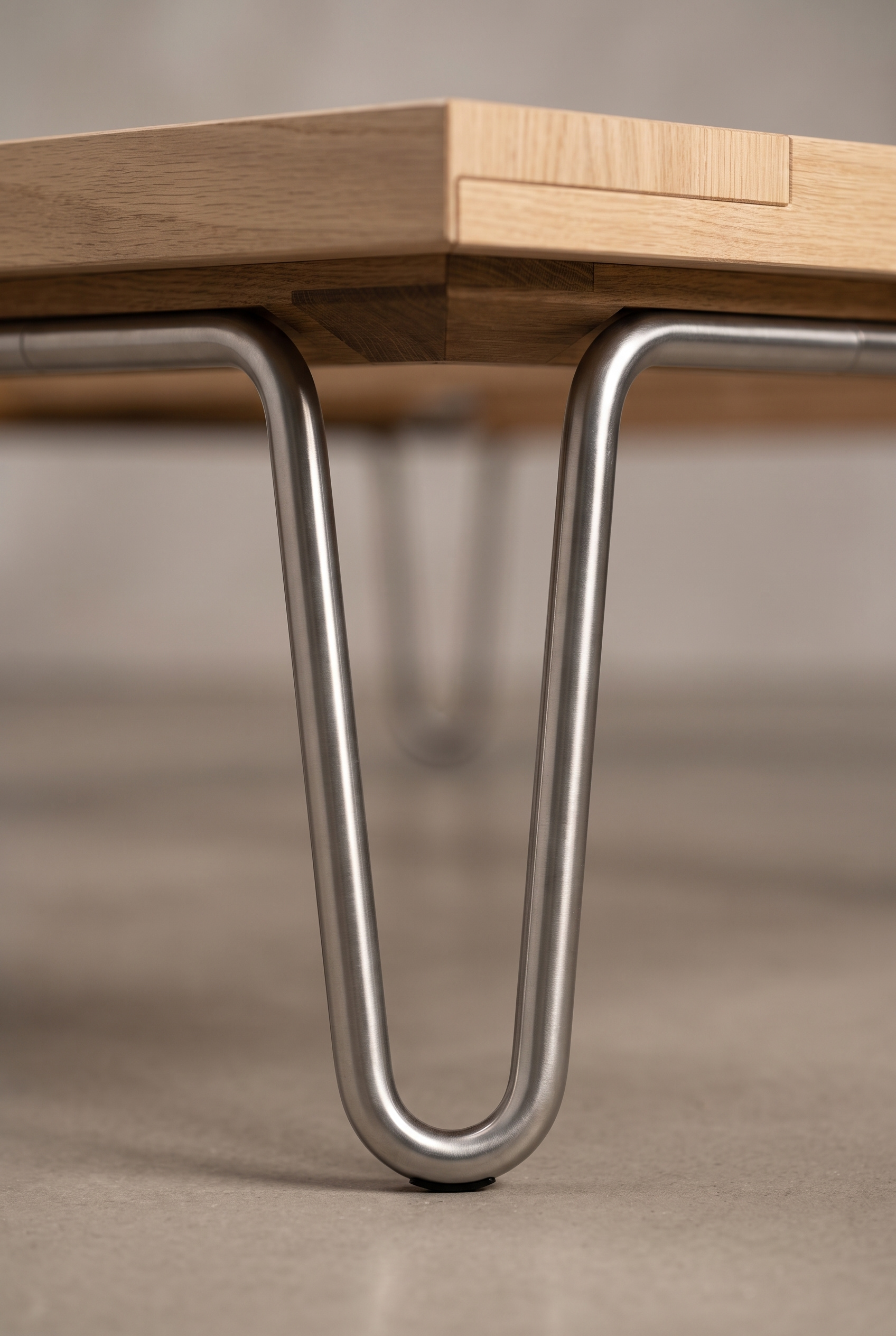 Architectural detail of the brushed stainless steel hairpin leg and solid oak underframe