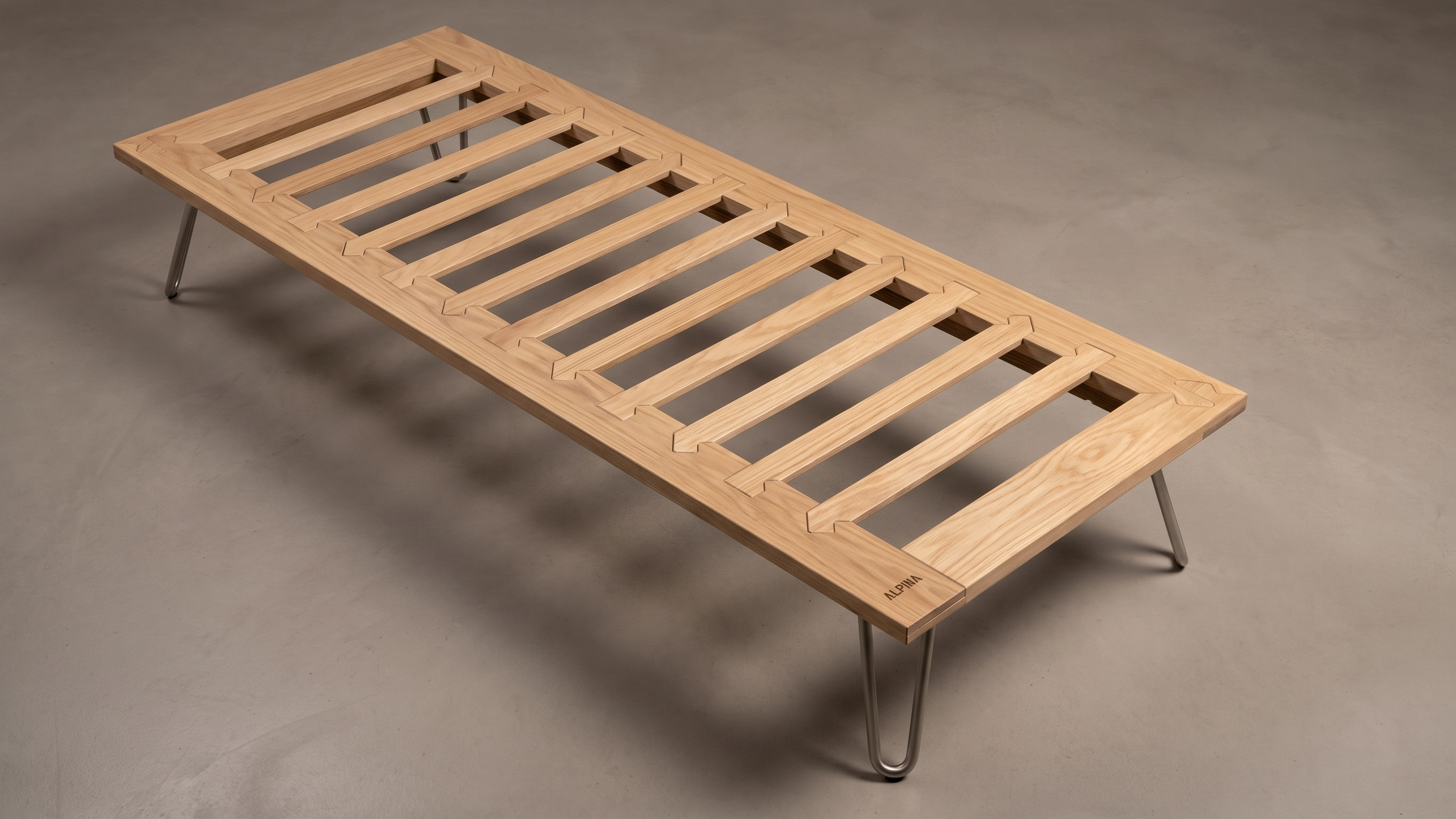 Elevated perspective of the Alpina bed base revealing the solid oak slats, Dolomiti corner joint, and engraved branding