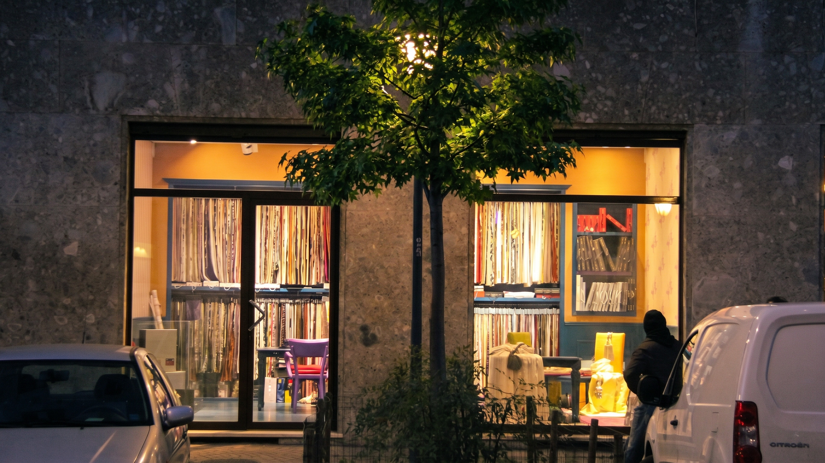 Evening exterior view of the Fili d'Aria windows glowing against the stone facade on Via Ozanam