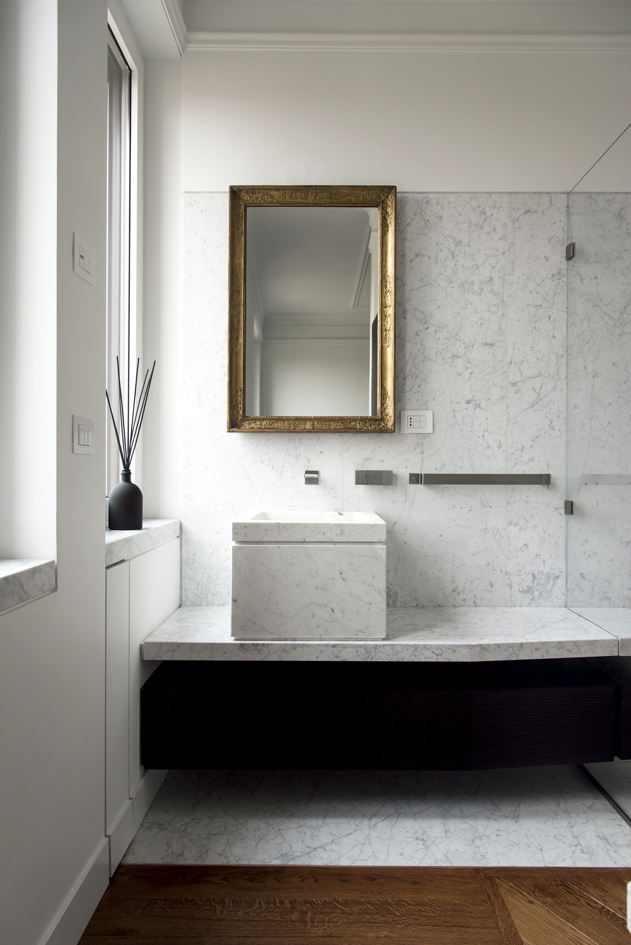 Close-up vertical shot highlighting the transition between the black oak and Carrara marble