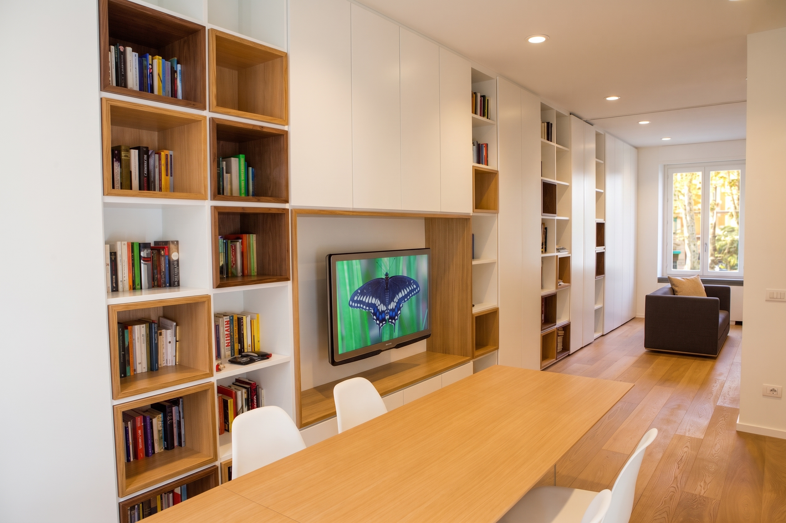 M401: Milan residential interior featuring full-height custom white cabinetry with natural oak box niches and timber dining table