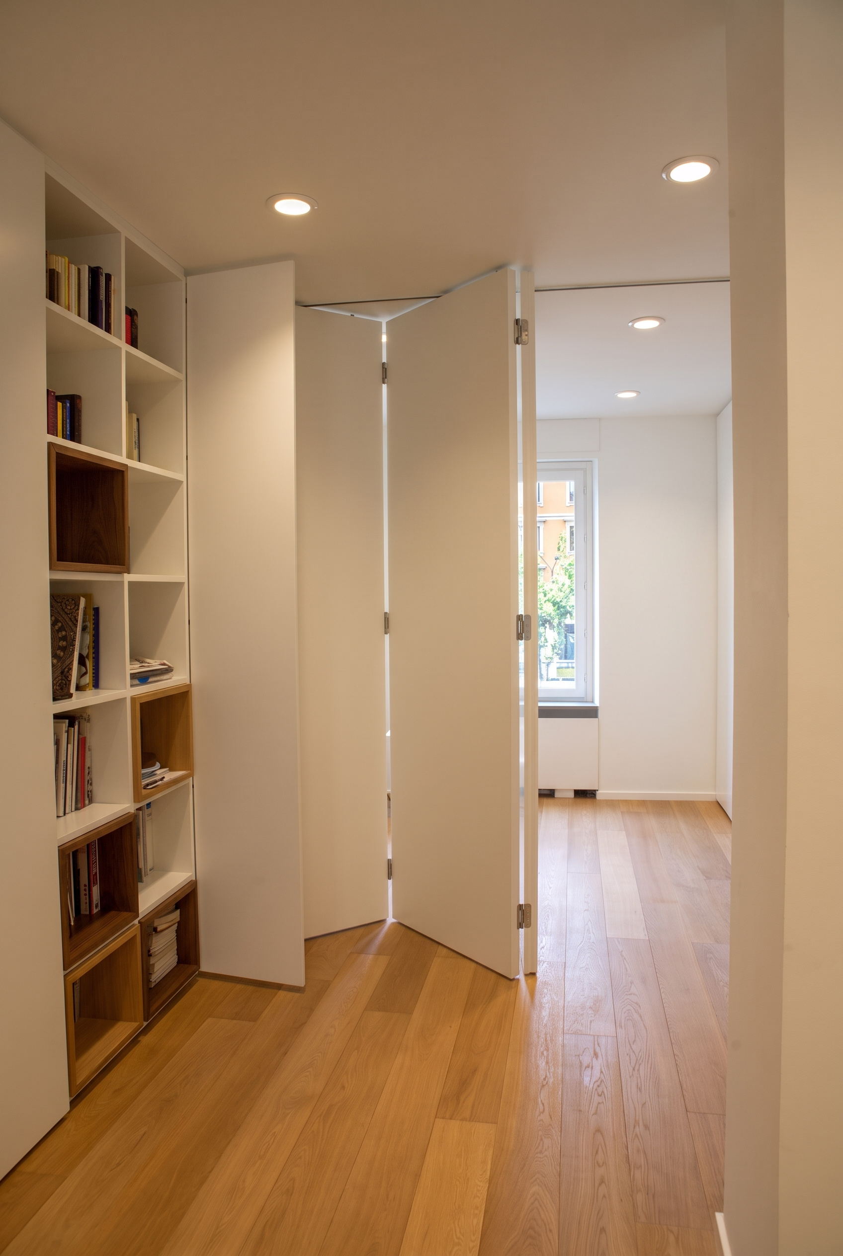 Full-height white folding partition doors opening to reveal flexible room configuration and oak flooring