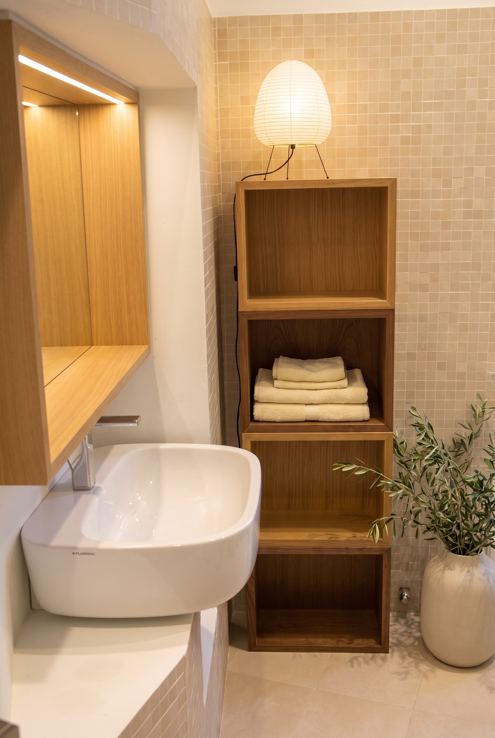 Bathroom detail featuring sculptural Flaminia washbasin, mosaic tile wall, custom oak modular shelving, and paper lantern light